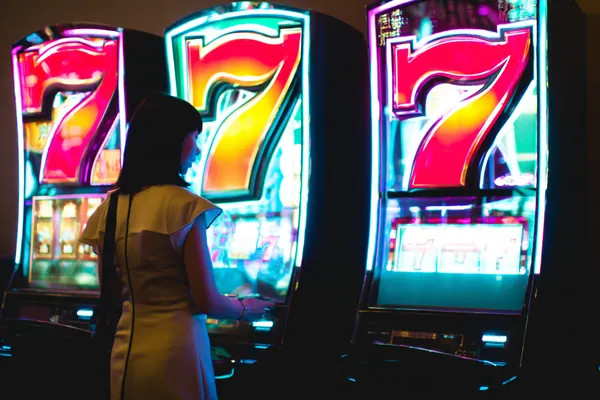 A woman smiling while playing online games on her laptop, surrounded by neon casino elements, showcasing TIKLUCK’s diverse game collection.