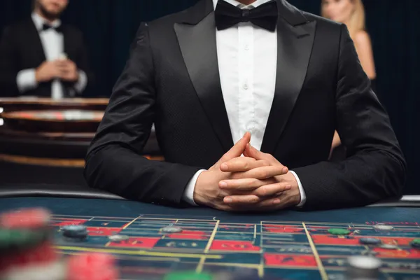 A woman in a luxurious green gown next to an ornate roulette wheel, capturing the upscale casino mood of TIKLUCK.